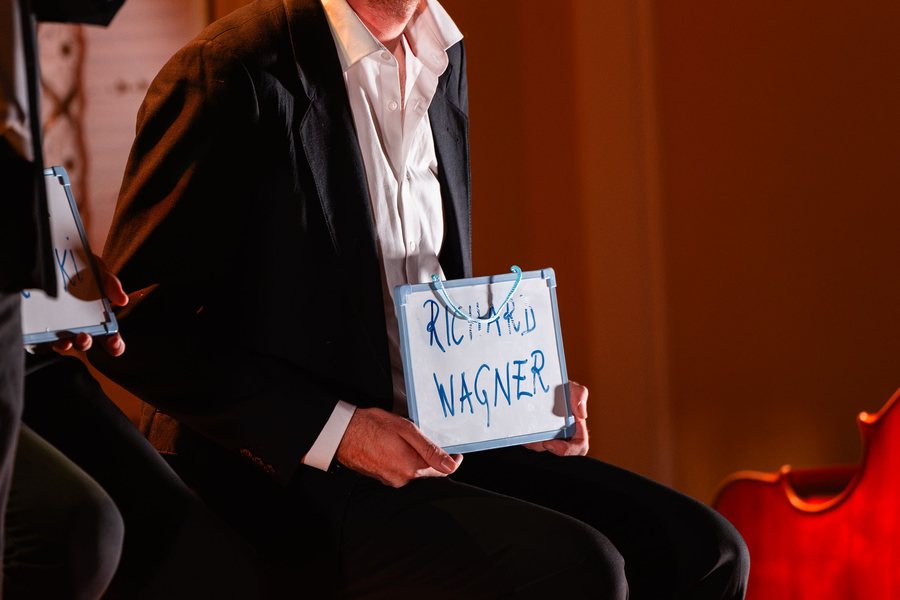 Nastopajoči drži napis Richard Wagner v zaključnem prizoru predstave.