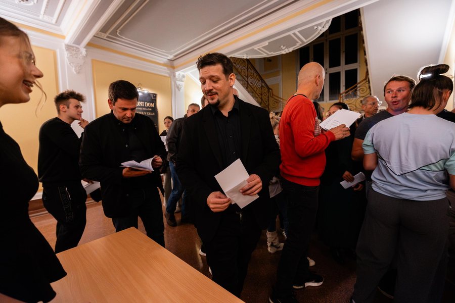 Skupina obiskovalcev z gledališkimi letaki v preddverju Narodnega doma Celje.